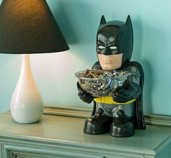 A batman themed chocolate holder on a grey top beside a table lamp
