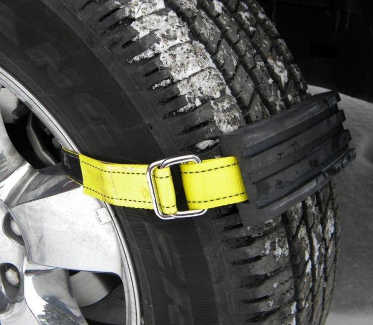A yellow and black colored tire gripper holding a lack tire in snow