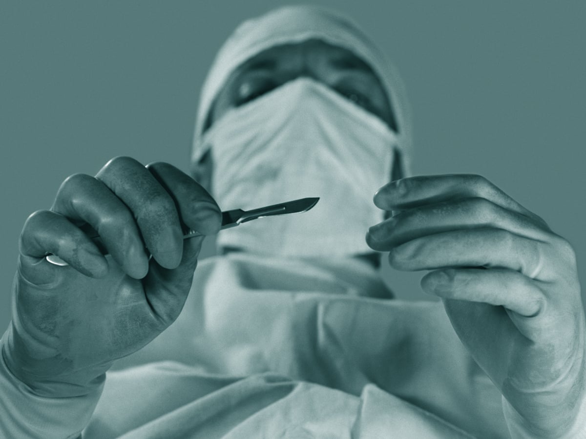 A doctor wearing a face mask while holding a scalpel