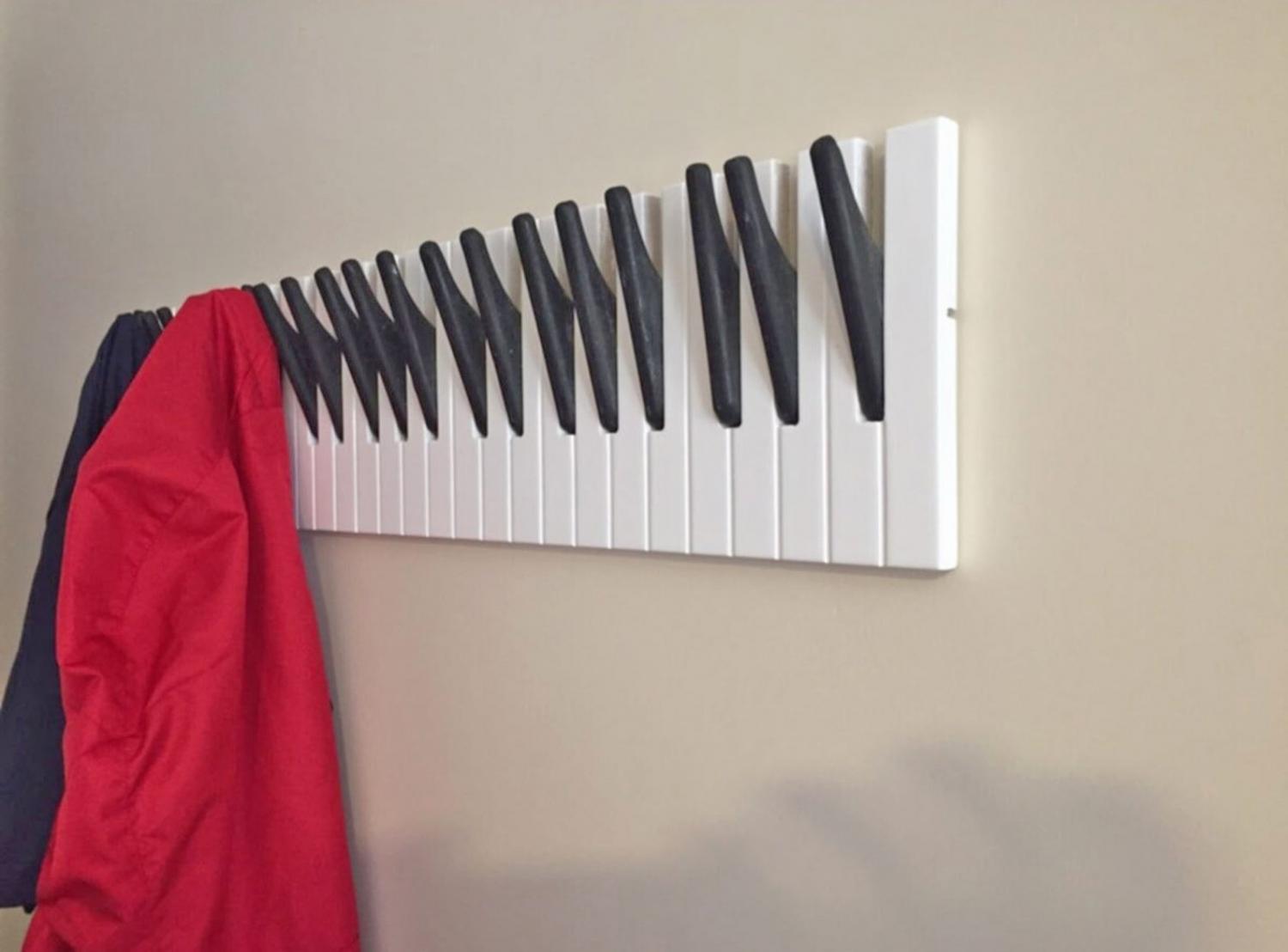 Red coat and black shirt hung on a Piano Keys Coat Rack on a skin wall