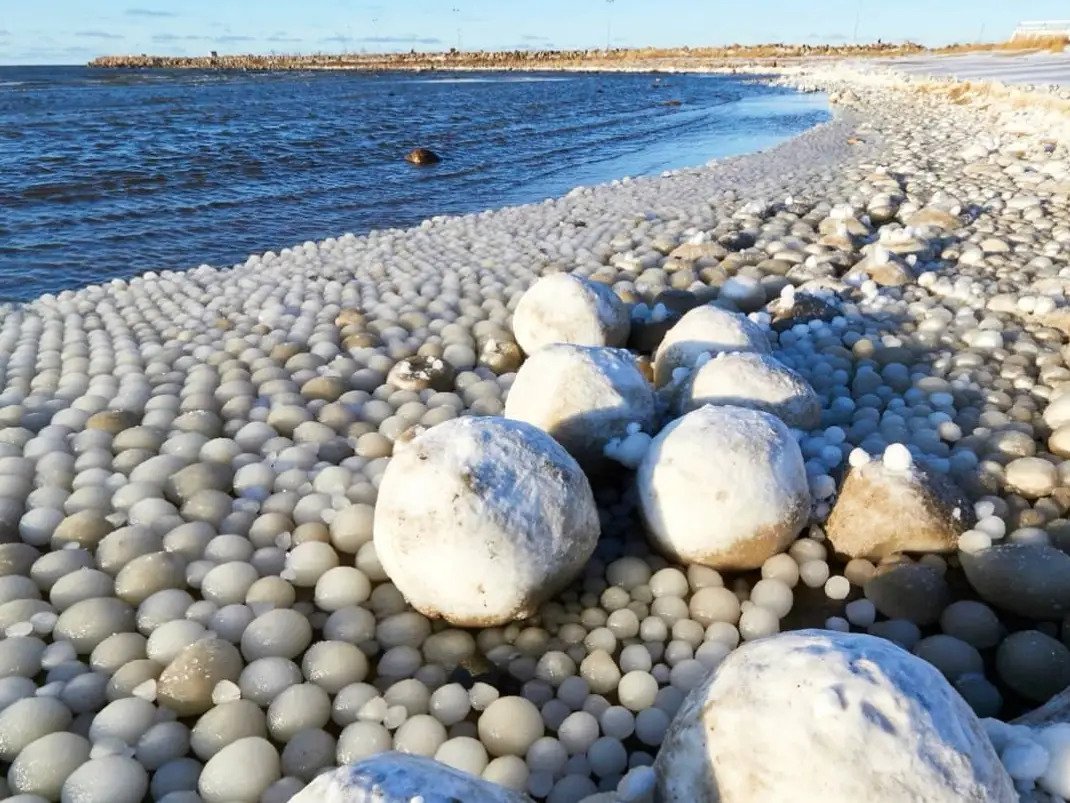 Football-sized and egg-sized ice balls on beach