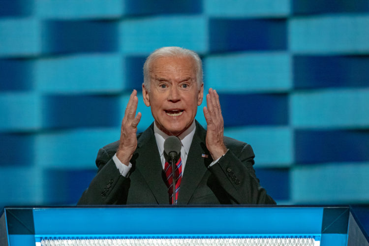 Joe Biden speaking on stage with his hands up