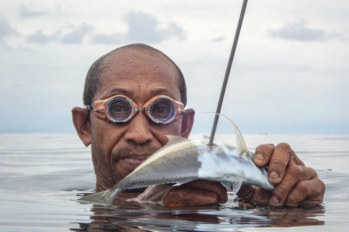 A close up shot of a bajau fisherman whoi is holding a fish