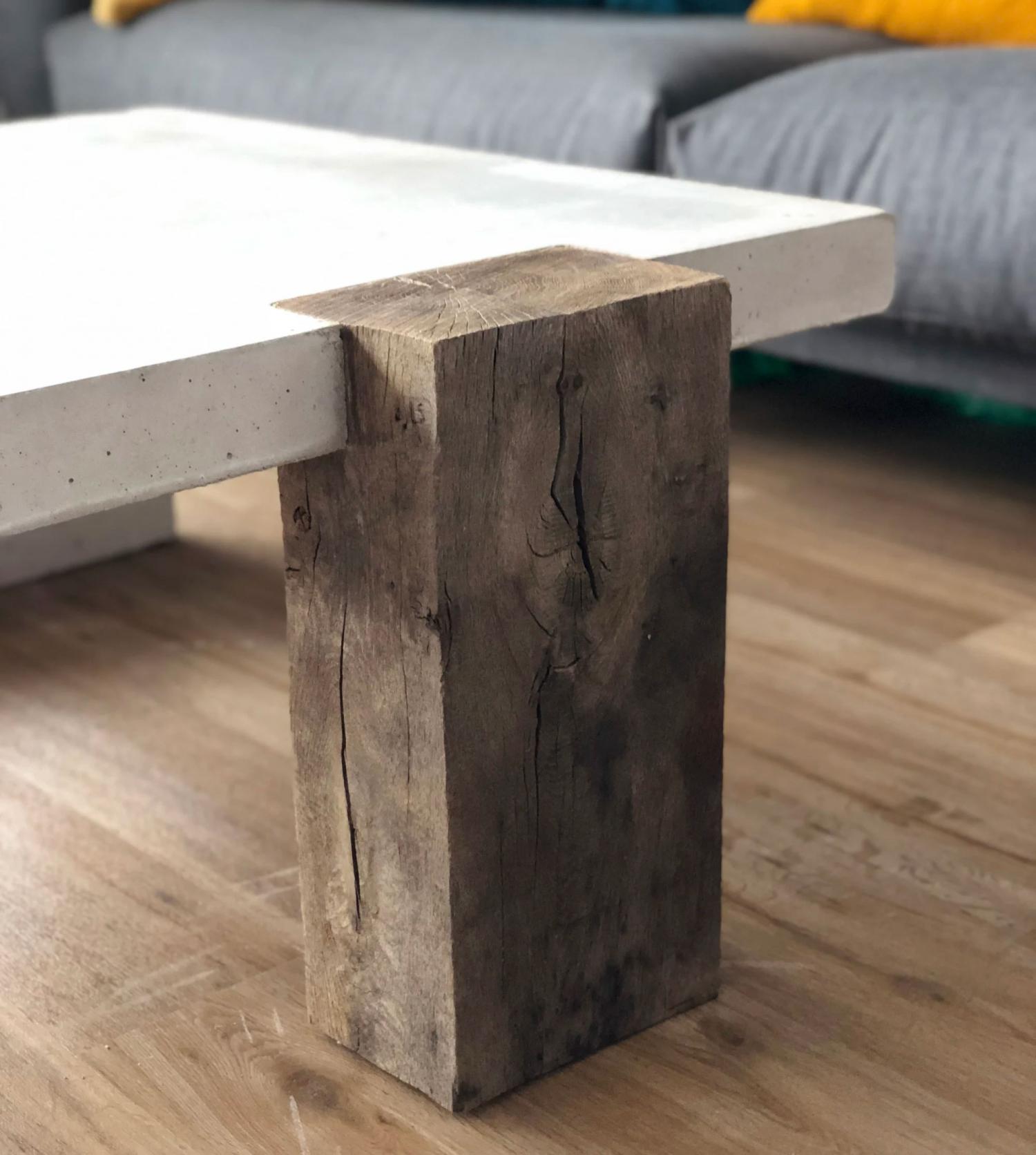 White ceramic concrete coffee table with a wooden block leg on a brown wooden floor