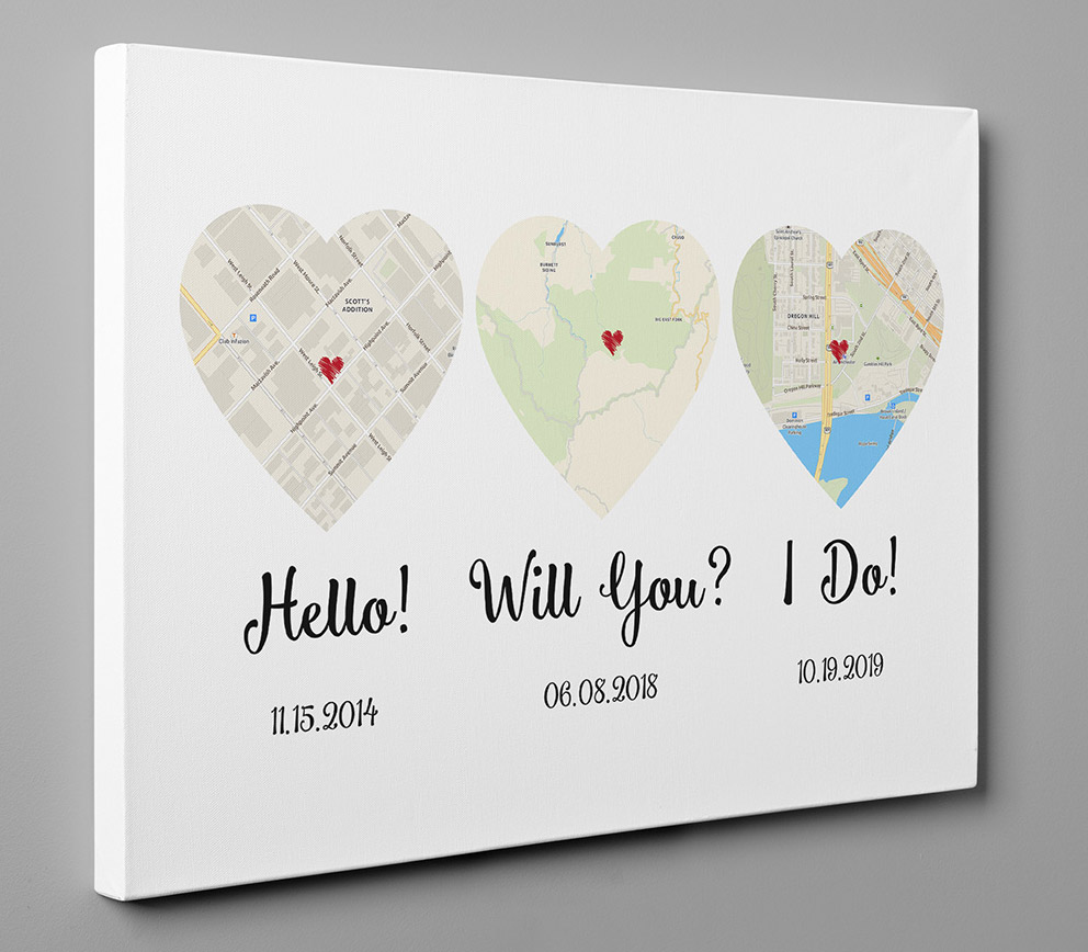 Heart-shaped maps with 'hello', 'will you, and 'I do' printed on a white background on a grey wall
