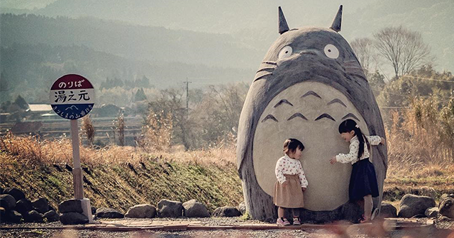 Two kids playing with the Totoro bus stop japan in the fields