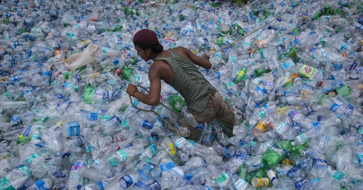 A boy in a giant heap of single-use plastic bottles