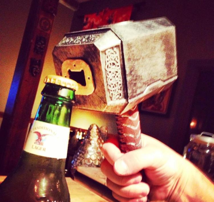 Thor hammer-shaped bottle opener opening a brown bottle