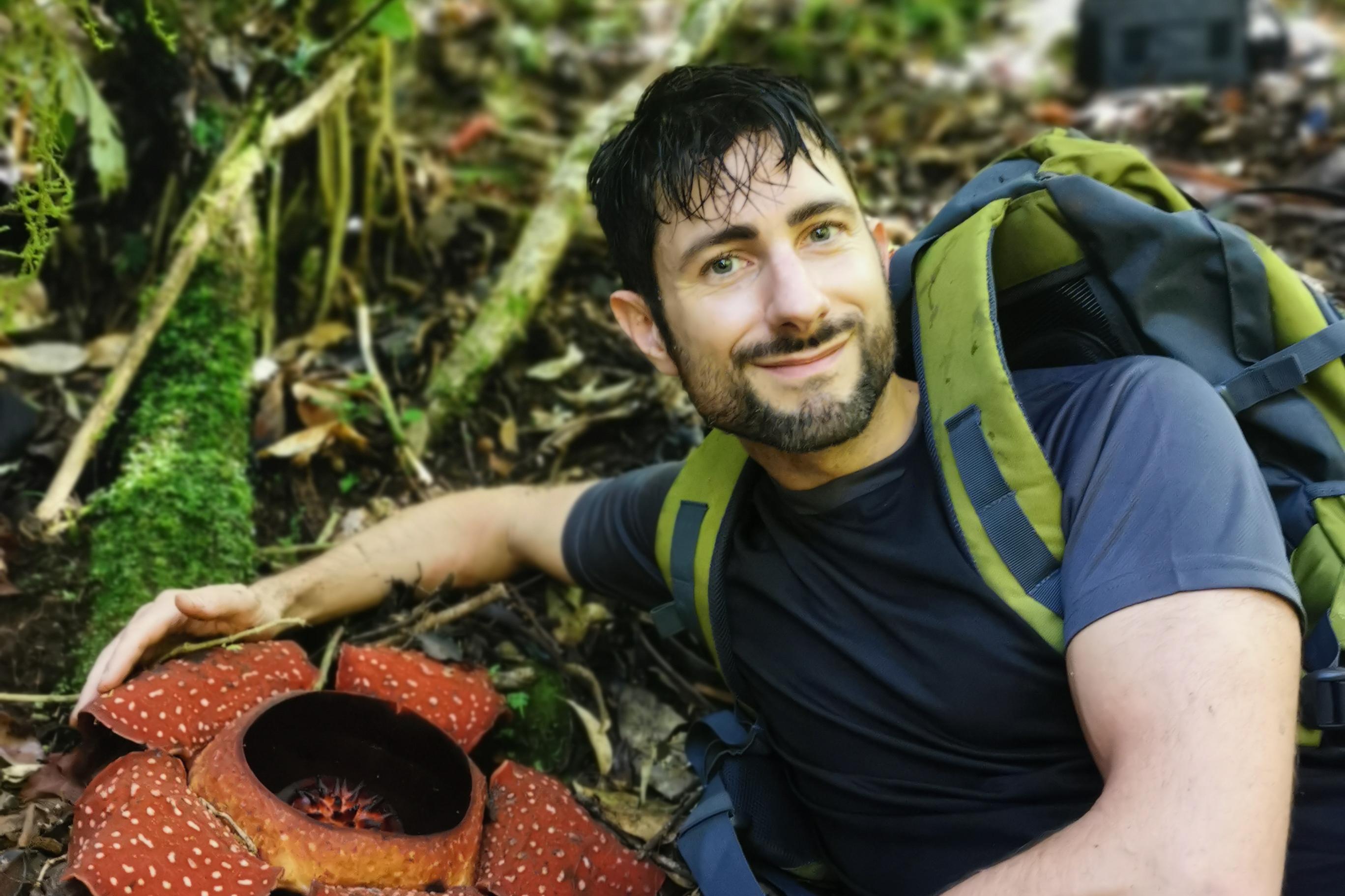 Chris Botanist siiting next to a Rafflesia flower in the forest