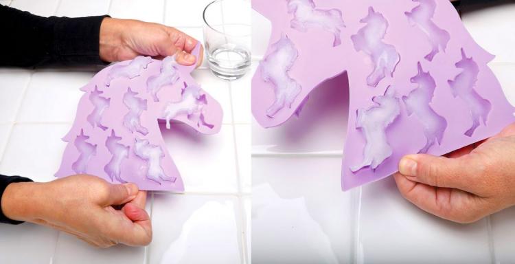 A pink-colored unicorn-shaped ice cube tray with unicorn -shaped ice cubes