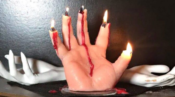 A realistic hand shaped candle bleeding while burning and revealing the flesh