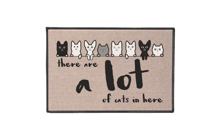 Black, white, and grey cats on a skin doormat, 'there are a lot of cats' in black printed on a skin doormat