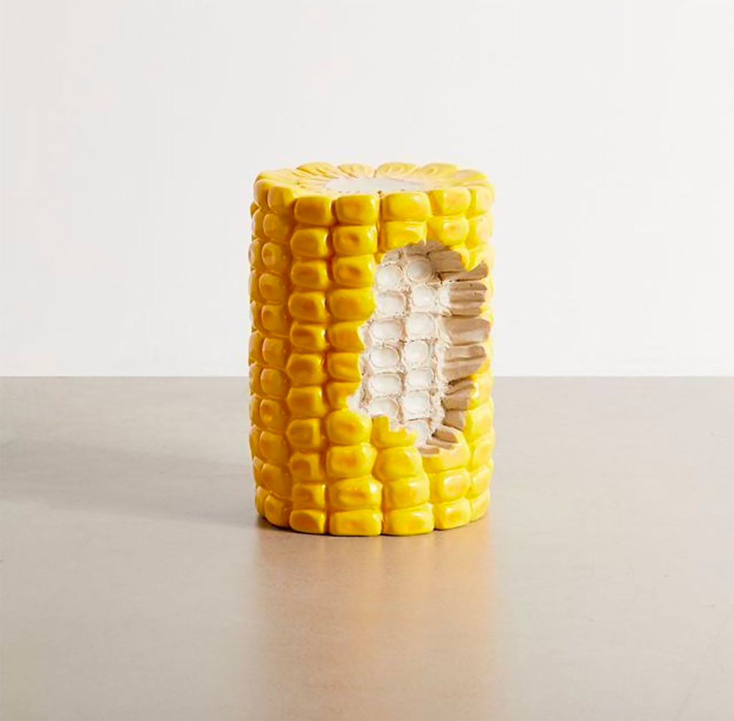 Half eaten realistic corn cob stool on a grey surface