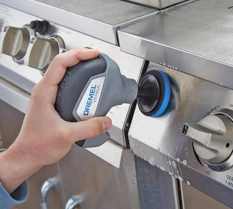 Grey colored cordless cleaner cleaning the switch side of the stainless steel stove
