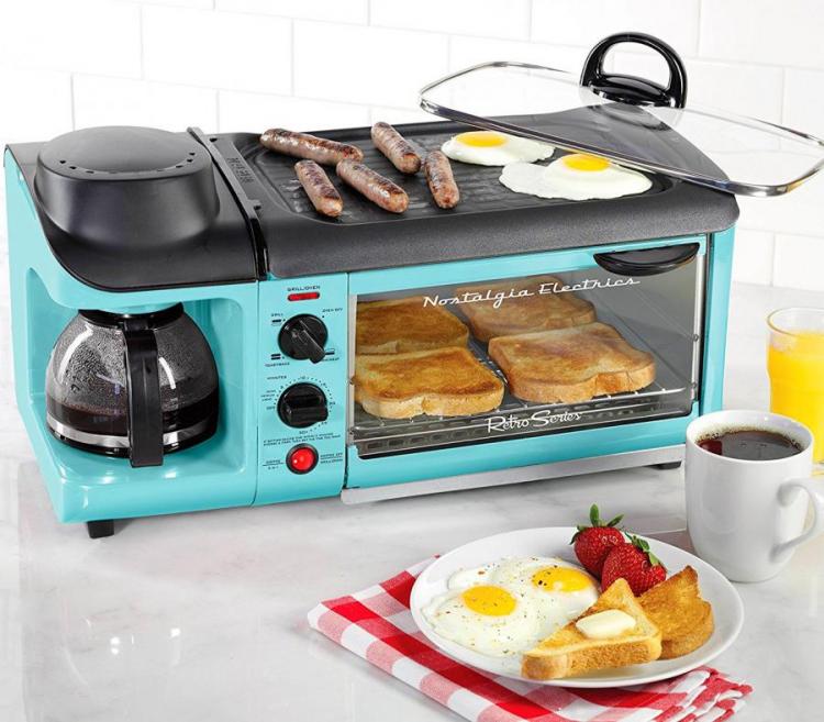 A blue and black colored huge oven for toasting bread, cooking eggs and sausages, and making coffee; two fried eggs with strawberries and toast on a white ceramic plate with a cup of black coffee