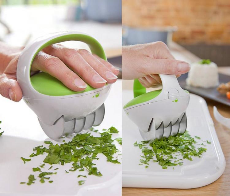 Green and white herb chopper chopping coriander on a white cutting board