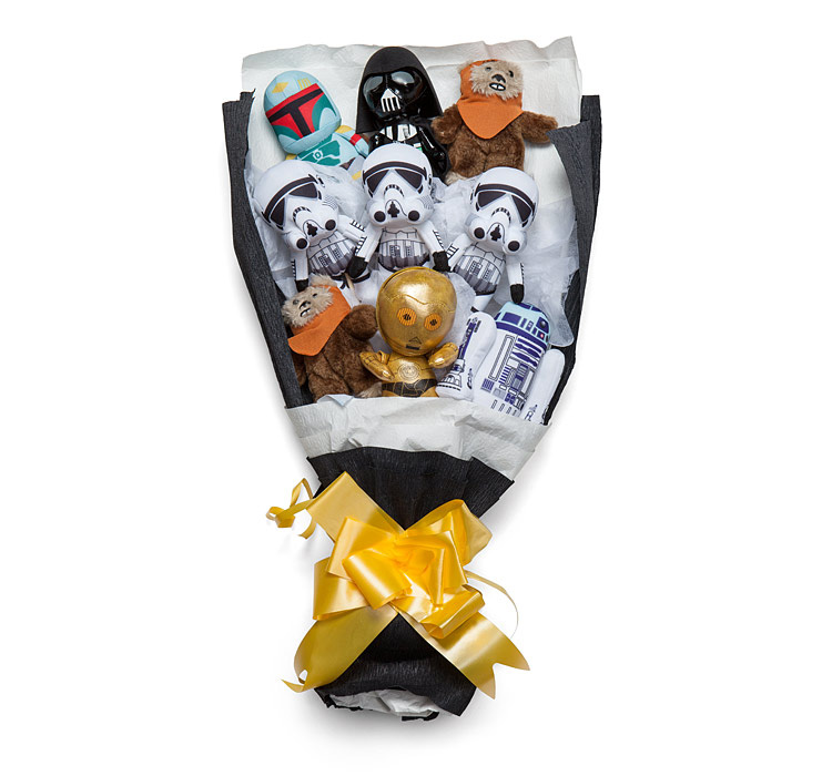 Star wars themed stuff toys like R2-D2 robot, Drath Vader toy and a lot more in a white and black paper wrap  and a golden ribbon on it