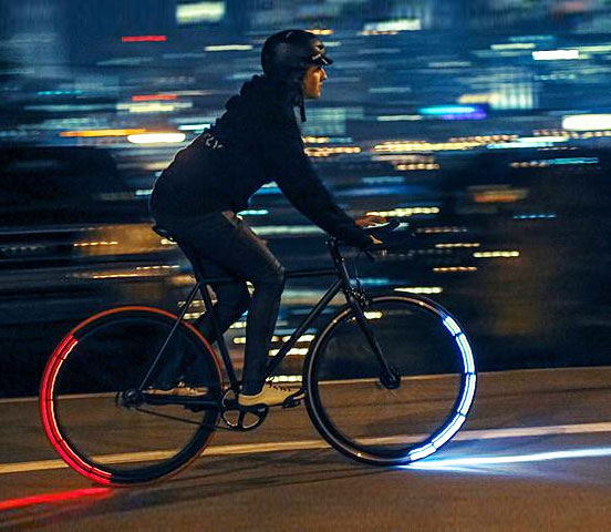 A person riding a red and blue illuminated wheeled bicycle