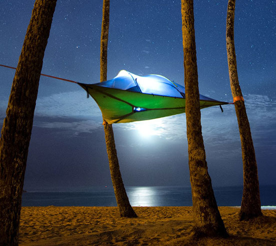 Green and blue colored hammock in front of the sea in the night