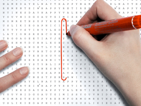A girl marking a word with a red marker on white word search gift paper