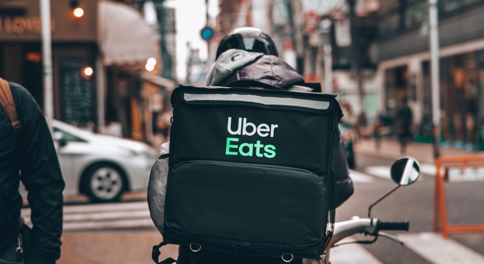 A food storage on the back of the motorcycle has a printed name of Uber Eats