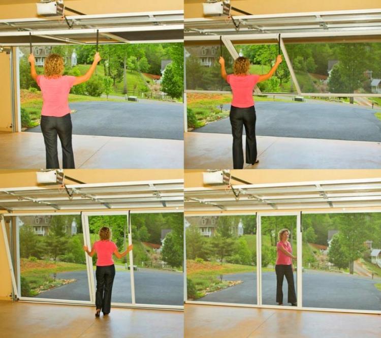A Lady wearing a pink shirt and black jeans rolling the mosquito screen in her garage
