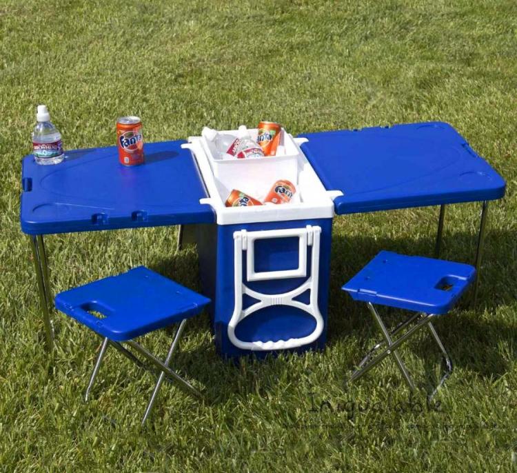 A blue-colored portable nad compact beer cooler with table and chairs on the ground