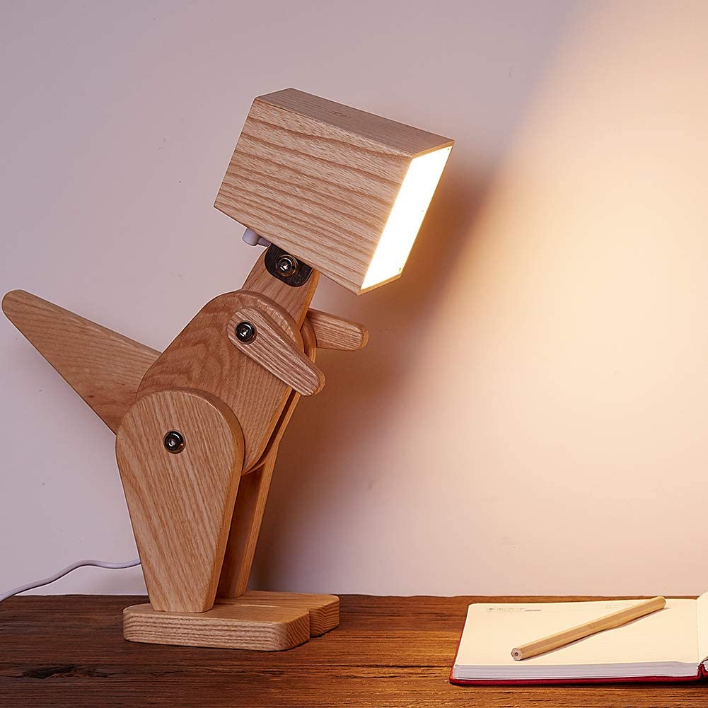 Brown colored dinosaur Adjustable Wooden Lamp on a dark brown table with notebook and pencil in the side