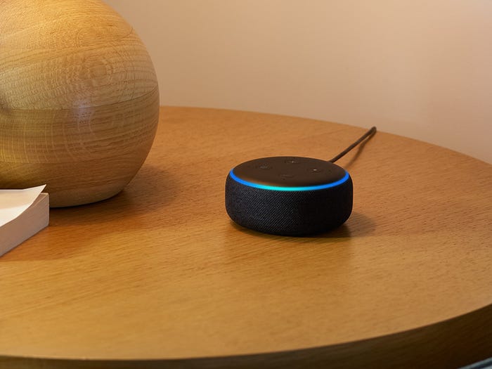 Black echo dot with blue details on a wooden table top
