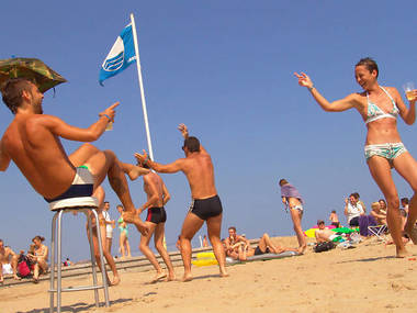Group of people at beach wearing trunks and swim suits having fun