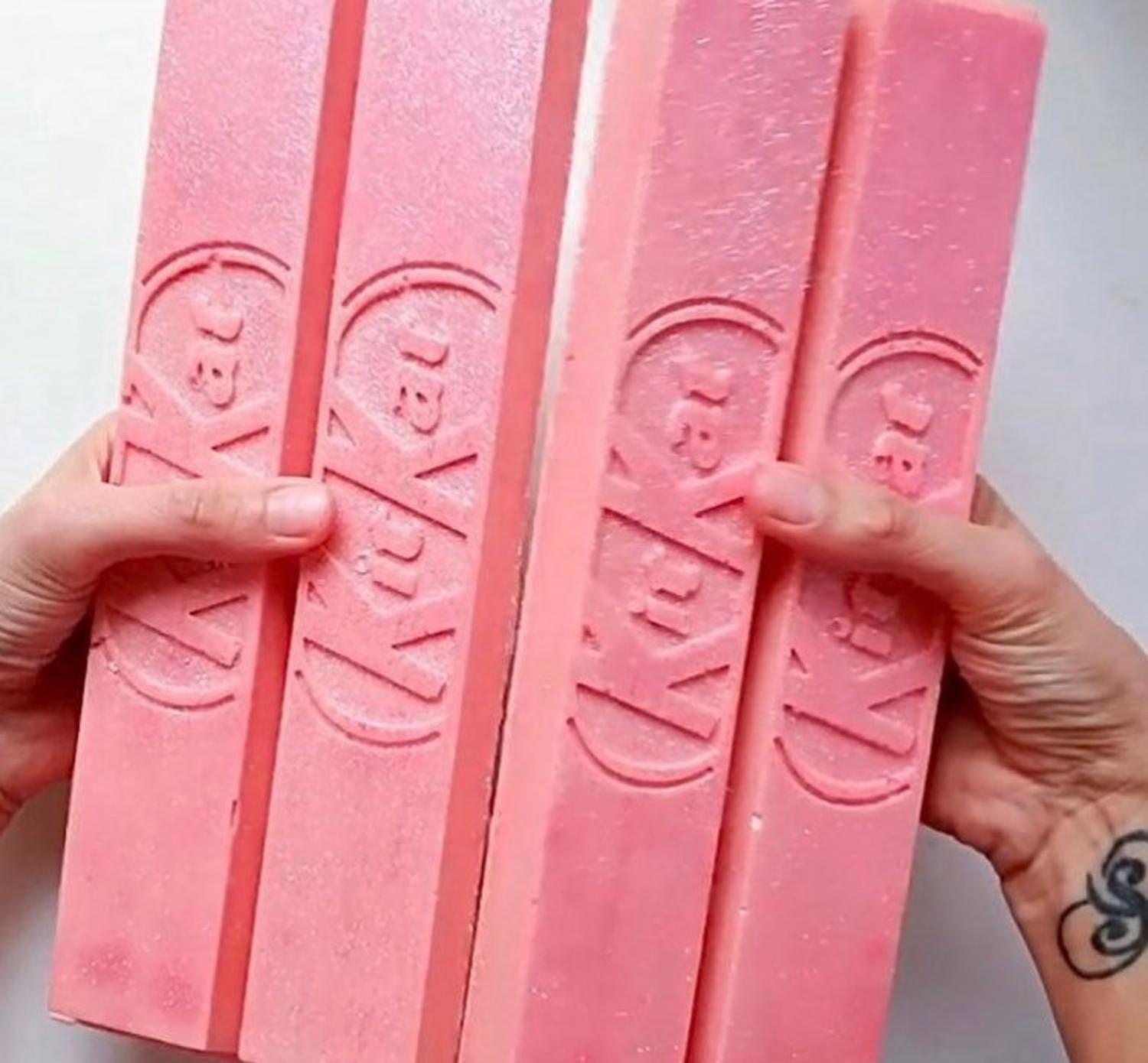 A man breaking the pink-colored Giant Kit-Kat Mold