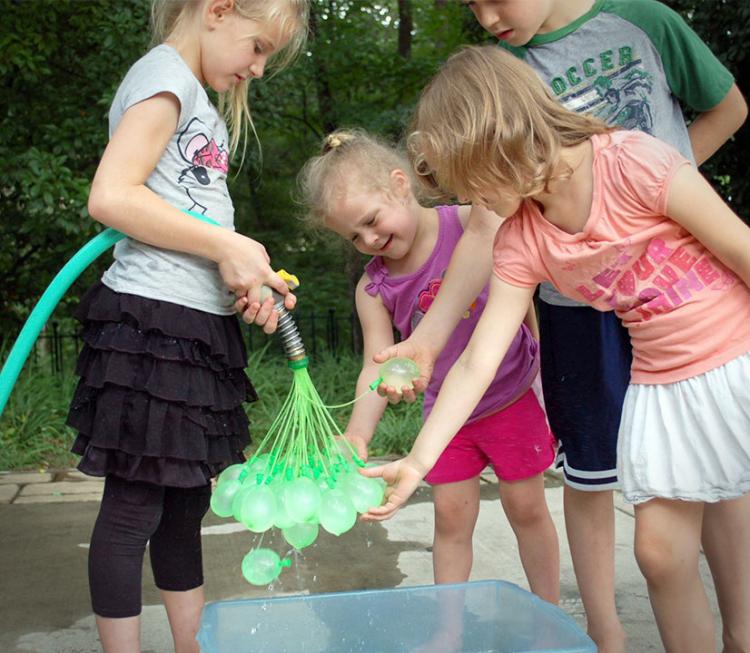 4 kids playing with green colored Bunch-o-Balloons in a garden