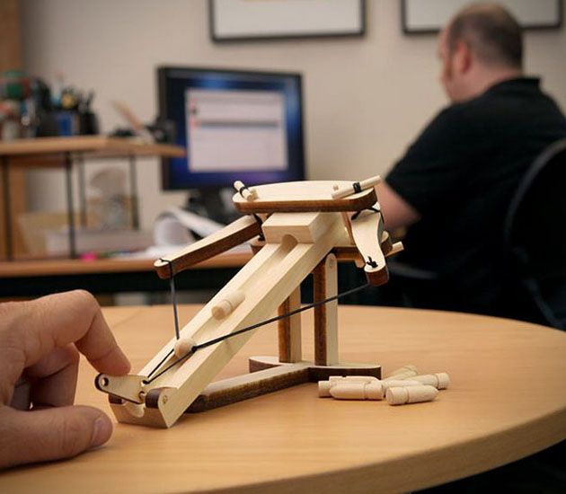 Little skin-colored wooden ballista kit on a brown wooden table top