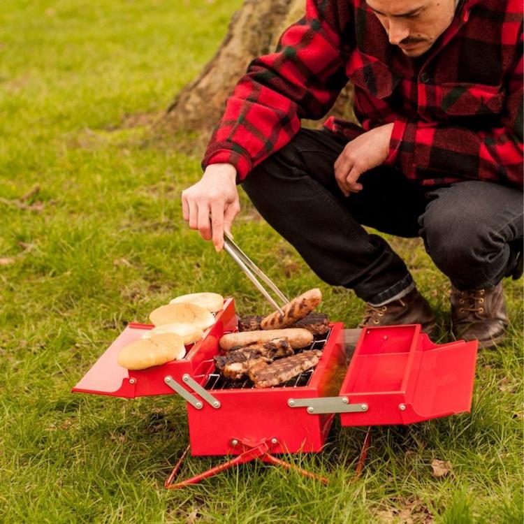 Red-colored toolbox grill grilling hotdogs and buns on the grass