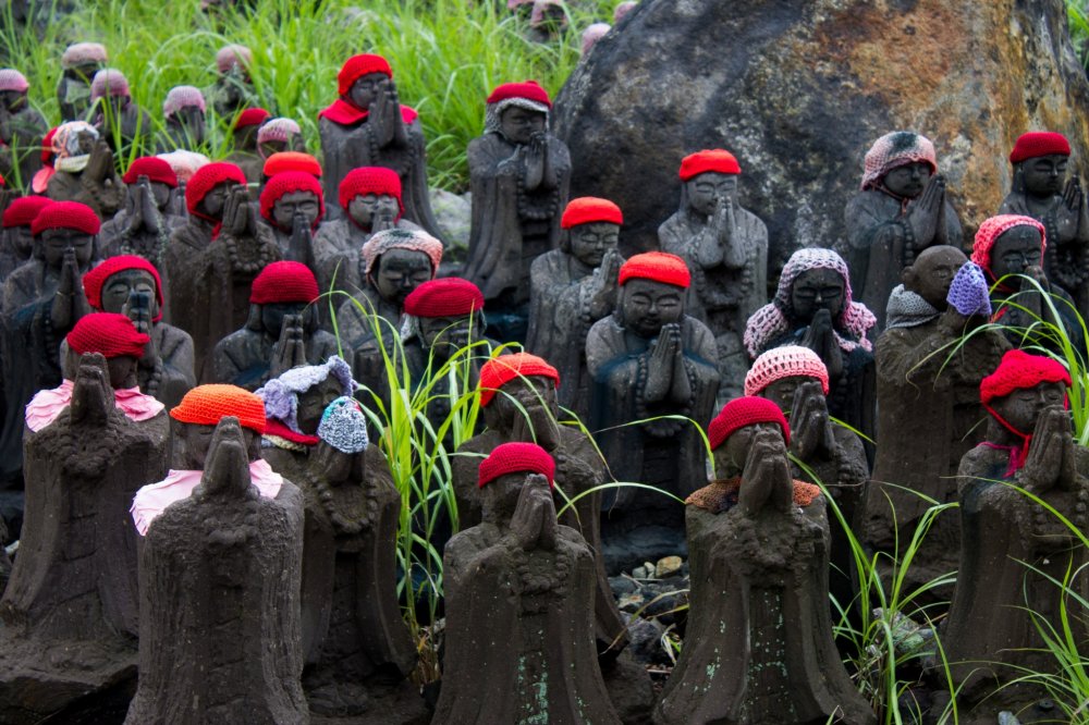 Some black colored statues covered with red, pink, blue-colored wool caps