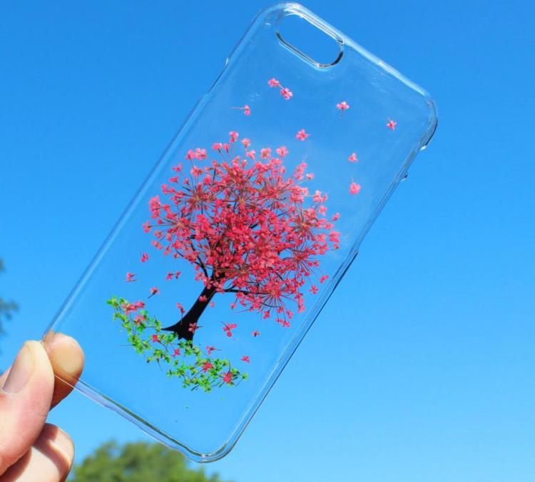 A transparent phone cover pressed with a real mini pink flower into a tree-shaped scenery