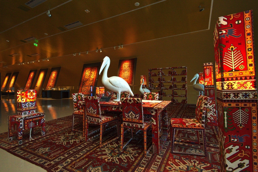 An inside picture of ANCM which contains multi colored carpeted chairs and white colored bird statues