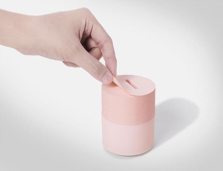 Light pink and pink sticky note piggy bank on a white surface