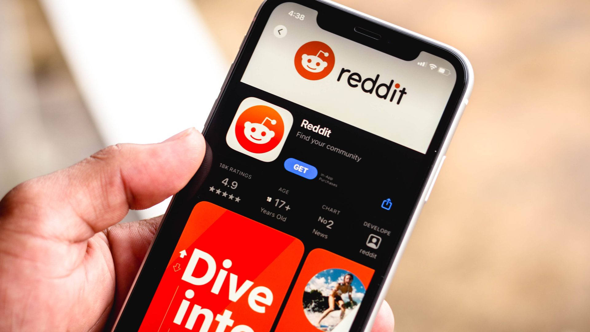 A hand holding a phone and showing reddit application