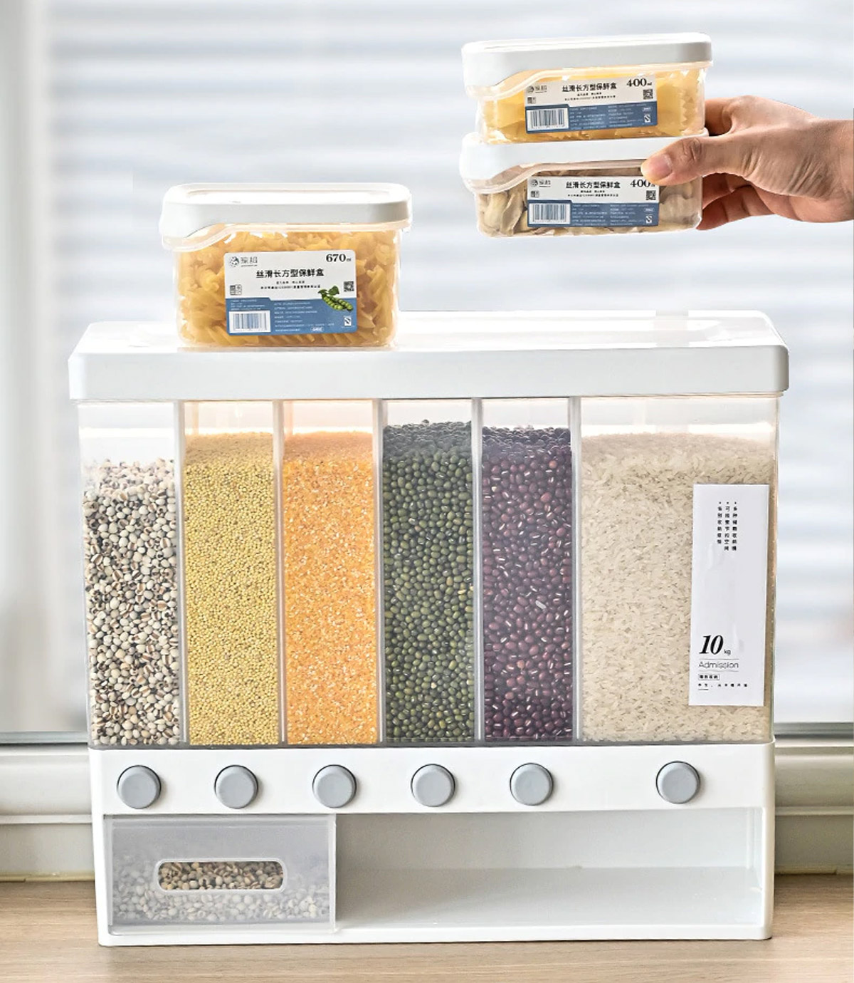 Transparent wall mounted food dispenser filled with multi-colored pulses and rice on a wooden surface