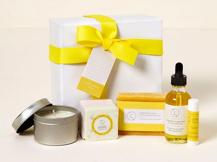 White and yellow themed pack of spa kit including white box with yellow ribbon, soap, candle, serum 