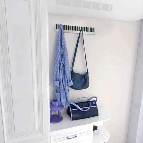 Blue shirt and a blue bag hung on a Piano Keys Coat Rack on a white wall