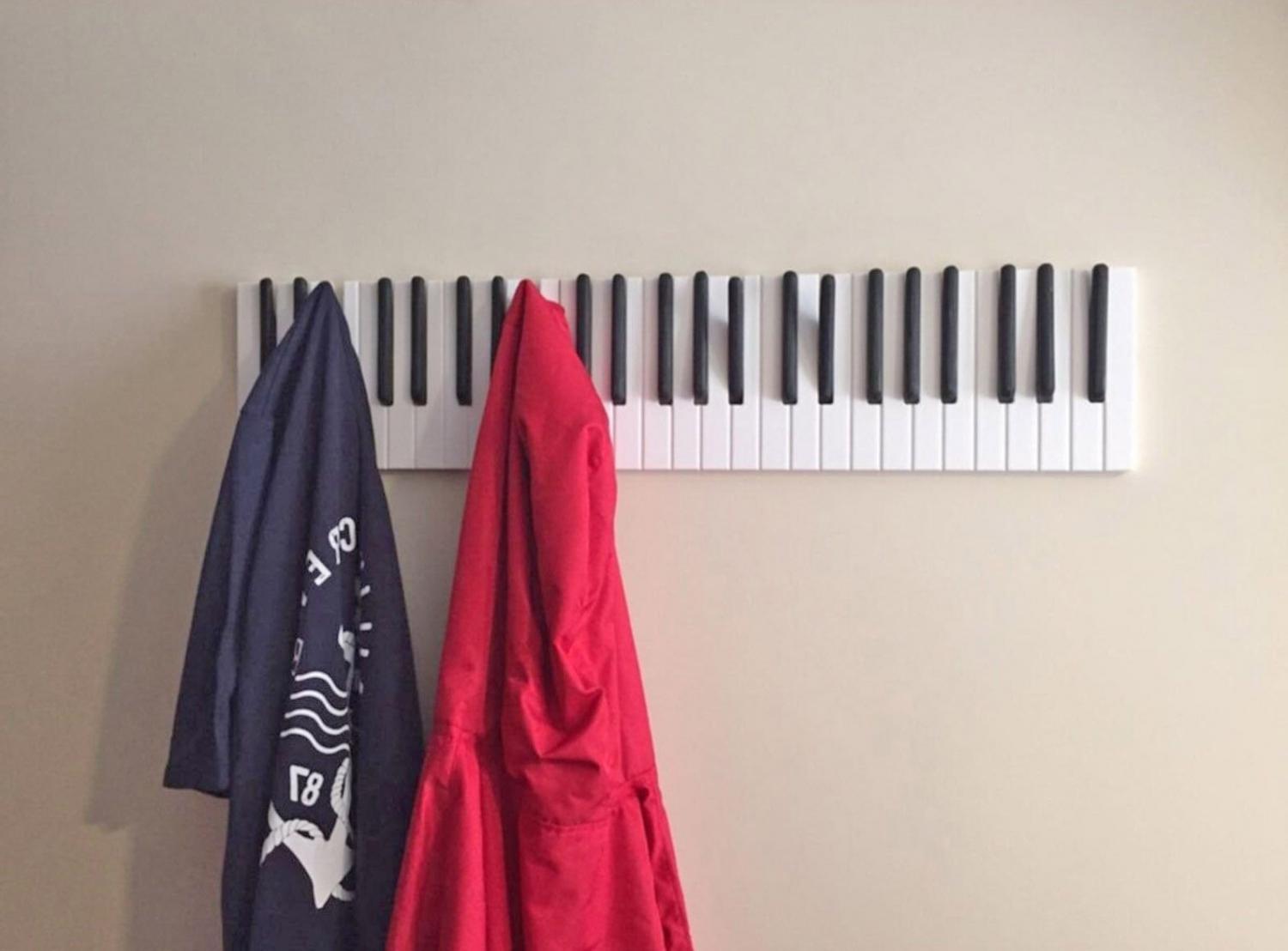 Red coat and black shirt hung on a Piano Keys Coat Rack on a skin-colored wall