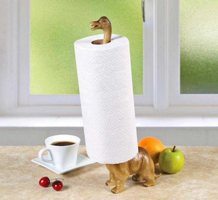 Skin-brown colored long neck dinosaur paper holder along  with cherries, a white cup of black coffee, green apple and orange on a skin marble surface