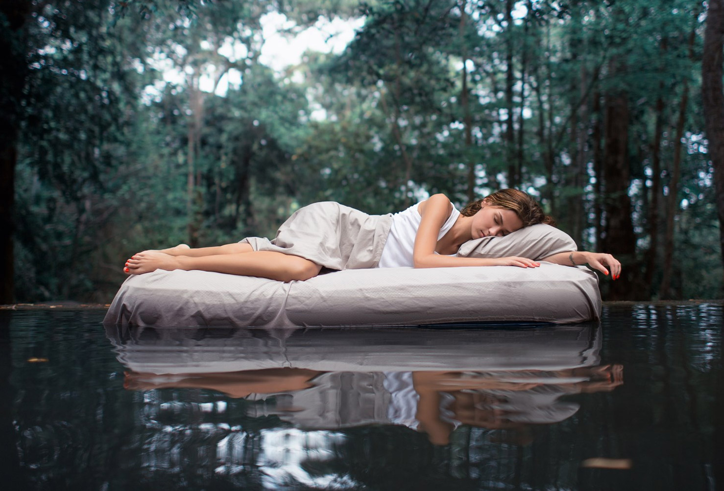 A white dress wearing girl sleeping on a white bed in the forest