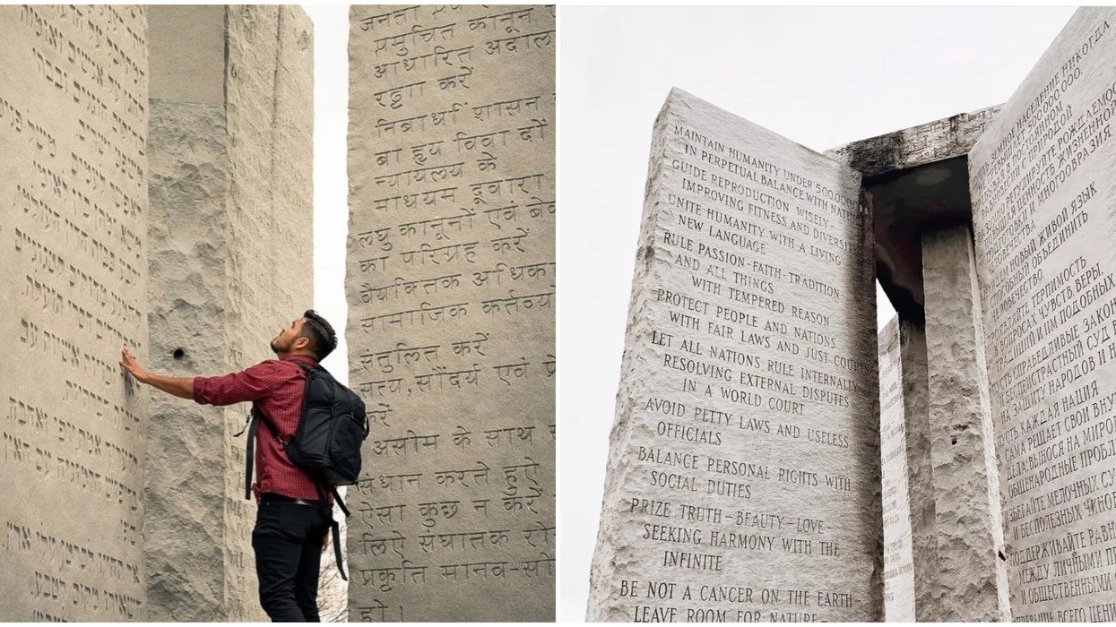 A red shirt and black pants wearing man touching the Georgia Guidestones in sanskrit