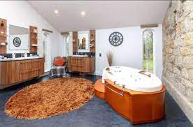 Brown colored wooden bath tub, a brown rug and dark brown wooden shelves in sam farmhouse bathroom