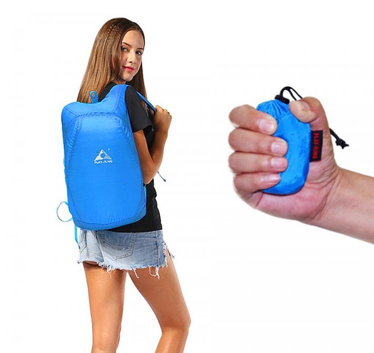 A hand is holding a blue colored tiny bag and a girl wearing it turning around