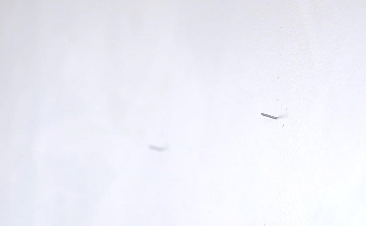 Two nails on a white wall