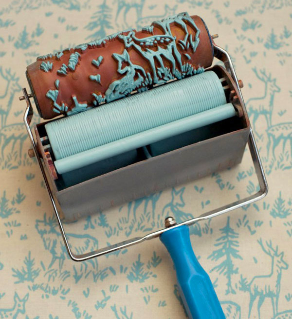 A deer and forest themed blue paint roller rolling on a white wall